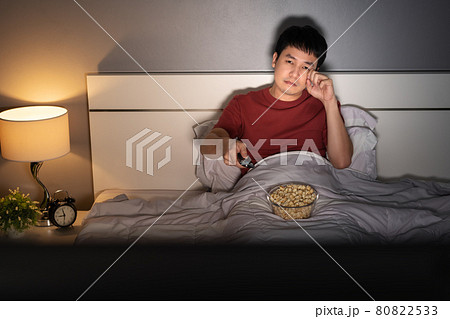 sad man watching television and crying on a bed at night (romantic movie) 80822533