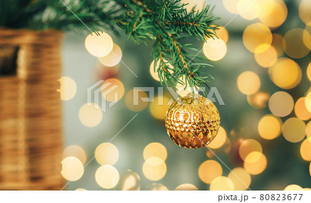 Golden Christmas bauble on blurry garlands background Golden Christmas bauble on blurry garlands background 80823677
