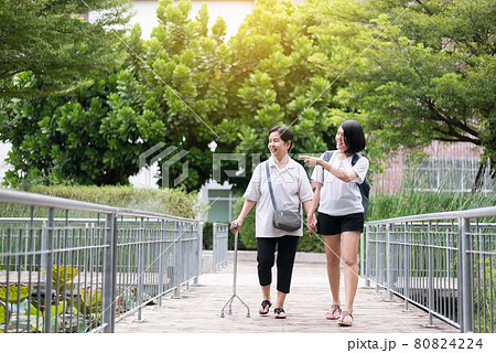Attempt elderly asian woman walking to do workout with stick at public park,Daughter take care and support Attempt elderly asian woman walking to do workout with stick at public park,Daughter take care and support 80824224