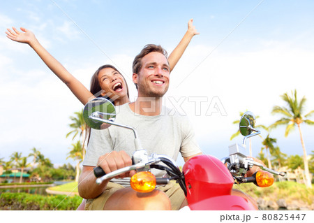 Road trip summer fun happy couple enjoying ride. Cheerful Asian woman passenger with arms up having fun man driver. Carefree tourists traveling driving on their summer vacation 80825447