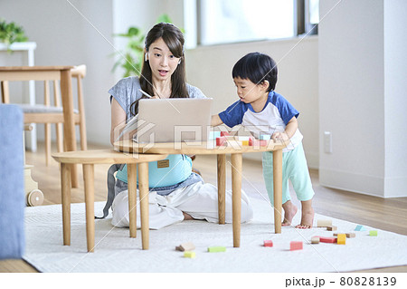 子供のいるリビングでオンライン会議をする女性 80828139