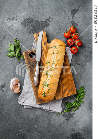 Sliced grilled bread with garlic and herbs, on gray stone table background, top view flat lay, with copy space for text Sliced grilled bread with garlic and herbs, on gray stone table background, top view flat lay, with copy space for text 80828327