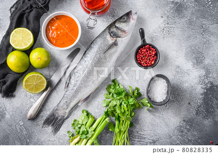 Raw seabass with spices and herbs ingredients on grey concrete background top view spacr for text. Raw seabass with spices and herbs ingredients on grey concrete background top view spacr for text. 80828335
