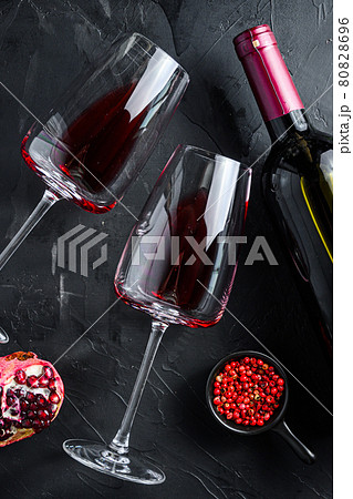 Glass of red wine with bottle on black textured background, top view. 80828696