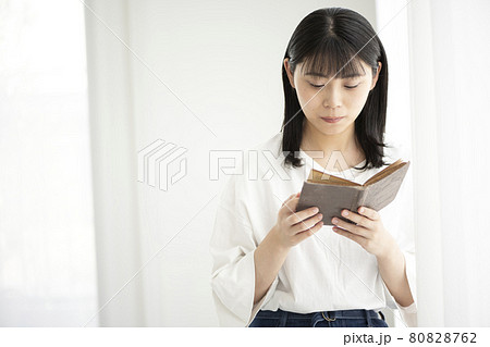 部屋の窓辺で古書を読む若い女性 80828762