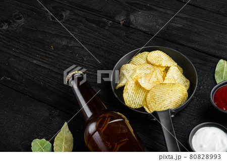 Home made potato chips, and bottle of beer , on black wooden background, with copy space for text 80828993