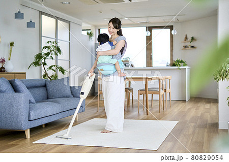 1歳半の息子を抱っこしながら掃除をする母親 1歳半の息子を抱っこしながら掃除をする母親 80829054