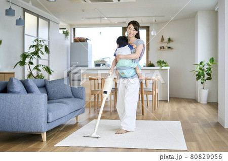 1歳半の息子を抱っこしながら掃除をする母親 1歳半の息子を抱っこしながら掃除をする母親 80829056