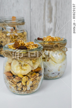 Healthy breakfast. Oatmeal Granola with greek yogurt and nuts banana muesli in jars on light background. Vegan, vegetarian and weight loss diet concept. Detox menu. Healthy breakfast. Oatmeal Granola with greek yogurt and nuts banana muesli in jars on light background. Vegan, vegetarian and weight loss diet concept. Detox menu. 80829197
