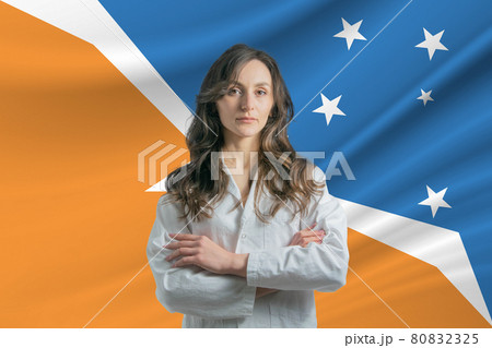 Medicine in Argentine Antarctica. Happy beautiful female doctor in medical coat standing with crossed arms against the background of the flag of Argentine Antarctica Medicine in Argentine Antarctica. Happy beautiful female doctor in medical coat standing with crossed arms against the background of the flag of Argentine Antarctica 80832325