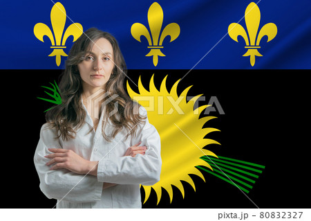 Medicine in Guadeloupe. Happy beautiful female doctor in medical coat standing with crossed arms against the background of the flag of Guadeloupe Medicine in Guadeloupe. Happy beautiful female doctor in medical coat standing with crossed arms against the background of the flag of Guadeloupe 80832327