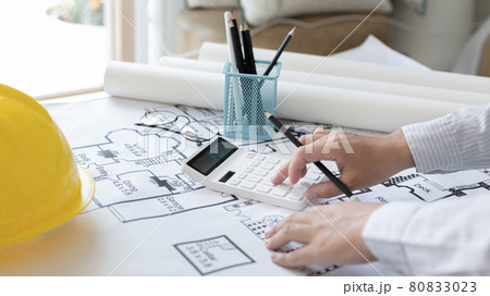 Male engineer or architect is pressing a calculator to calculate the building's structure and balance, Architects or engineers are designing buildings using calculator to calculate the physical struct Male engineer or architect is pressing a calculator to calculate the building's structure and balance, Architects or engineers are designing buildings using calculator to calculate the physical struct 80833023