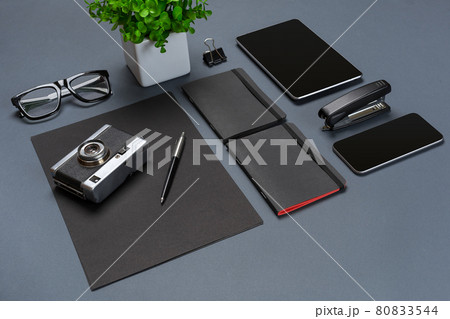A set of black office accessories, glasses, old camera and tablet on gray background A set of black office accessories, glasses, old camera and tablet on gray background 80833544