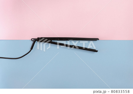 Electric curling iron with ceramic plates on blue and pink background. Top view. Electric curling iron with ceramic plates on blue and pink background. Top view. 80833558