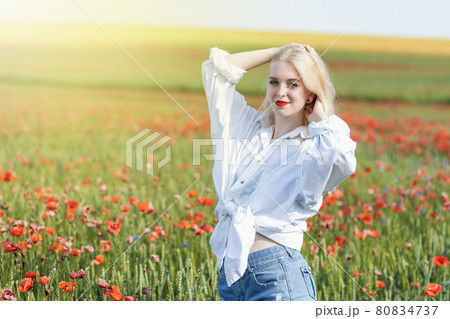 Attractive young girl posing in a field with red poppies. 80834737