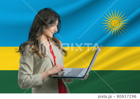 Freelance in Rwanda. Beautiful young woman freelancer uses laptop computer against the background of the flag of Rwanda 80837296
