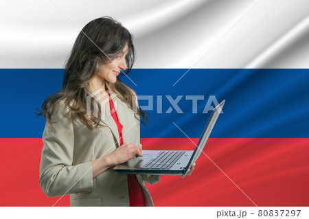 Freelance in Russia. Beautiful young woman freelancer uses laptop computer against the background of the flag of Russia Freelance in Russia. Beautiful young woman freelancer uses laptop computer against the background of the flag of Russia 80837297