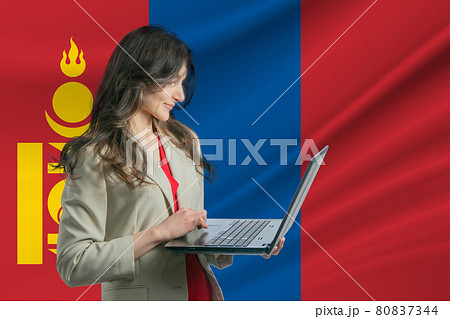 Freelance in Mongolia. Beautiful young woman freelancer uses laptop computer against the background of the flag of Mongolia Freelance in Mongolia. Beautiful young woman freelancer uses laptop computer against the background of the flag of Mongolia 80837344