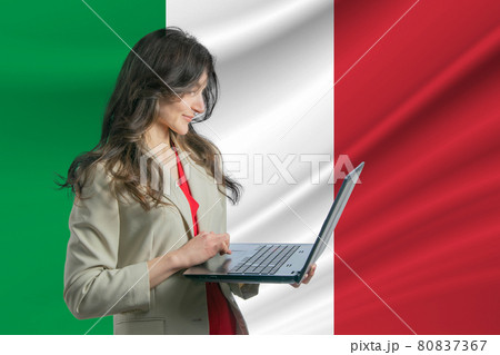 Freelance in Italy Beautiful young woman freelancer uses laptop computer against the background of the flag of Italy 80837367