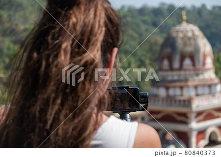 Young woman taking picture of Indian Temple Young woman taking picture of Indian Temple 80840373