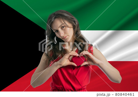 Love Kuwait A girl holds a heart on her chest in her hands against the background of the flag of Kuwait The concept of patriotism 80840461