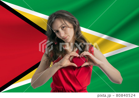 Love Guyana. A girl holds a heart on her chest in her hands against the background of the flag of Guyana. The concept of patriotism Love Guyana. A girl holds a heart on her chest in her hands against the background of the flag of Guyana. The concept of patriotism 80840524