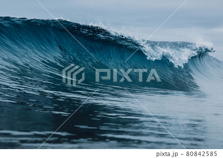 Perfect barrel wave on sandy beach. Breaking ocean wave with cloudy weather Perfect barrel wave on sandy beach. Breaking ocean wave with cloudy weather 80842585