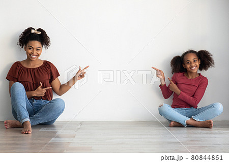 Cheerful african american mother and daughter pointing at copy space 80844861