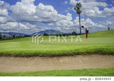 Golfers putting golf balls on the golf course in the morning. Golf man putting on green for birdie on the green golf.  80844944