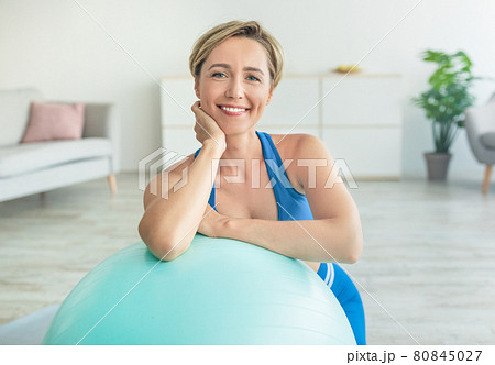 Smiling Sporty Woman Exercising Leaning On Fitness Ball At Home Smiling Sporty Woman Exercising Leaning On Fitness Ball At Home 80845027