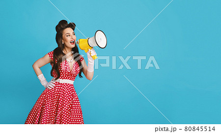 Pinup woman in retro outfit making announcement, shouting into megaphone on blue background, banner with free space Pinup woman in retro outfit making announcement, shouting into megaphone on blue background, banner with free space 80845514