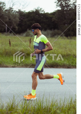 Young professional male triathlete, runner in motion on open road. Concept of sport, lifestyle, activity. Side view 80845521