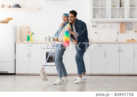 Joyful muslim couple cleaning floor and having fun in kitchen 80845738