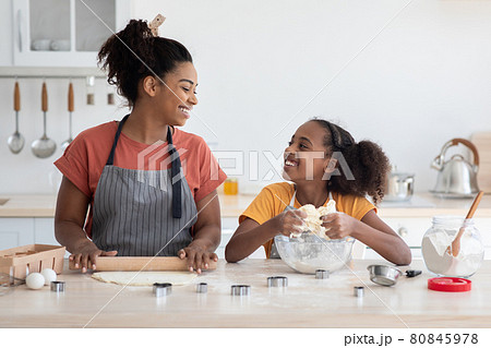 Joyful african american mother and daughter baking together 80845978