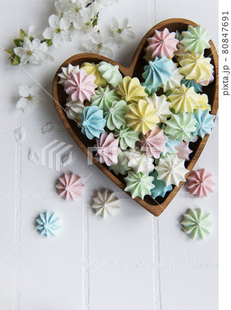 Small colorful meringues in the  wooden heartshaped bowl 80847691
