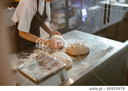 Baker kneads dough for bread at table in craft bakery shop closeup 80850978
