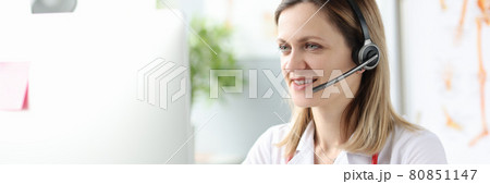 Portrait smiling doctor headphones microphone workplace closeup 80851147
