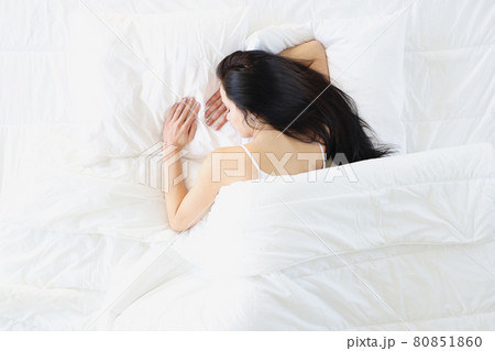 Sleeping brunette woman lies on white bed 80851860