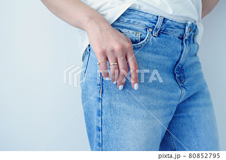 Woman's hands with perfect manicure wears in denim trousers and white basic t-shirt. 80852795
