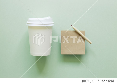 Brown kraft memo pad, pencil, paper coffee cup on green background. top view, copy space 80854898