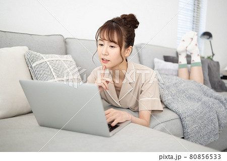 ソファでパソコンを見る笑顔の女性 80856533