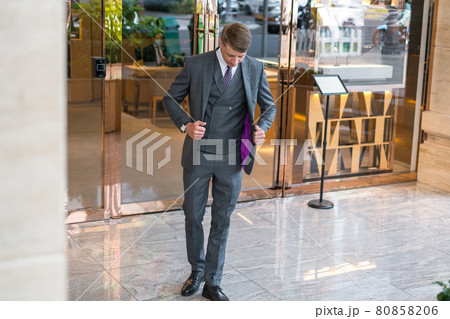 Handsome businessman in grey formal suit standing near modern building  80858206