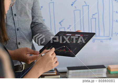 Two businesspeople analyzing stock market investment strategy together in meeting room. 80860081