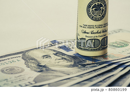 A coiled 100 dollar bill which rests on another angled 100 dollar bill isolated on white background 80860199