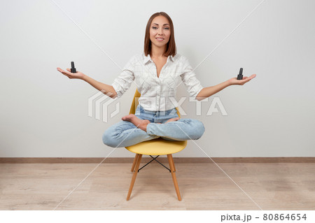 Beautiful woman in casual clothes sitting on a chair holding bottles of nail varnish over white background 80864654