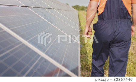 Close up of a young engineer hand is checking the operation of sun and cleanliness of photovoltaic solar panels on a sunset. Close-up of modern photovoltaic solar battery. Close up of a young engineer hand is checking the operation of sun and cleanliness of photovoltaic solar panels on a sunset. Close-up of modern photovoltaic solar battery. 80867446