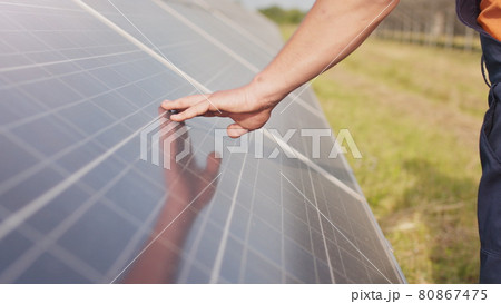 Close up of a young engineer hand is checking the operation of sun and cleanliness of photovoltaic solar panels on a sunset. Close-up of modern photovoltaic solar battery. 80867475