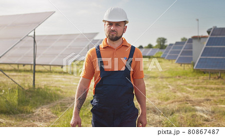 Industrial man engineer in uniform walking through solar panel field for examination. Ecological construction. Solar power station, Green energy concept. Solar station development and energy 80867487