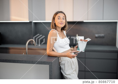 Woman with takeaway food and phone at kitchen Woman with takeaway food and phone at kitchen 80867710