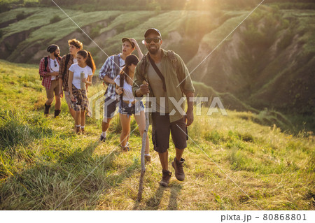Group of friends, young men and women walking, strolling together during picnic in summer forest, meadow. Lifestyle, friendship, 80868801